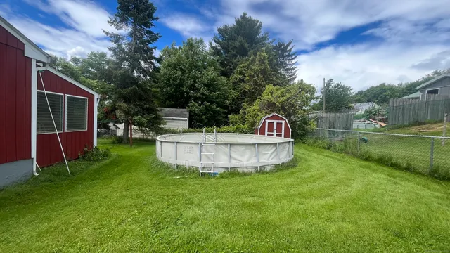 a view of a tiny house with a yard and sitting area
