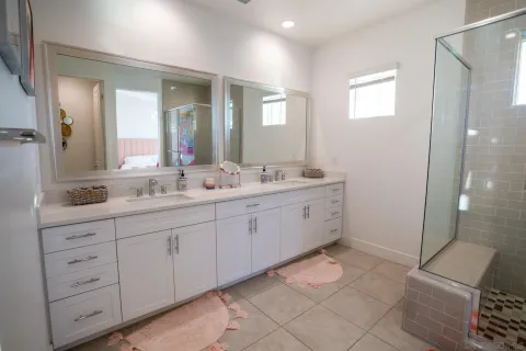 a spacious bathroom with a double vanity sink a mirror and a shower