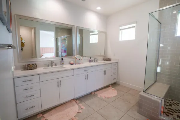 a spacious bathroom with a double vanity sink a mirror and a shower