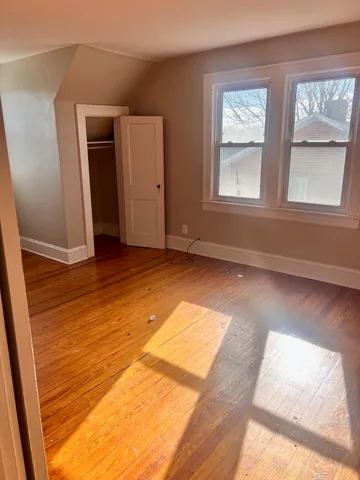 a view of an empty room with wooden floor and windows