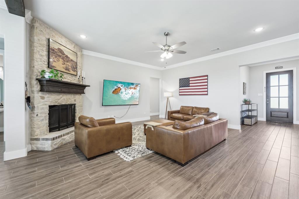 800 Majors Road Van Alstyne, TX 75495 - Photo 8 of 40 Living room featuring visible vents, wood finish floors, a fireplace, ceiling fan, and crown molding