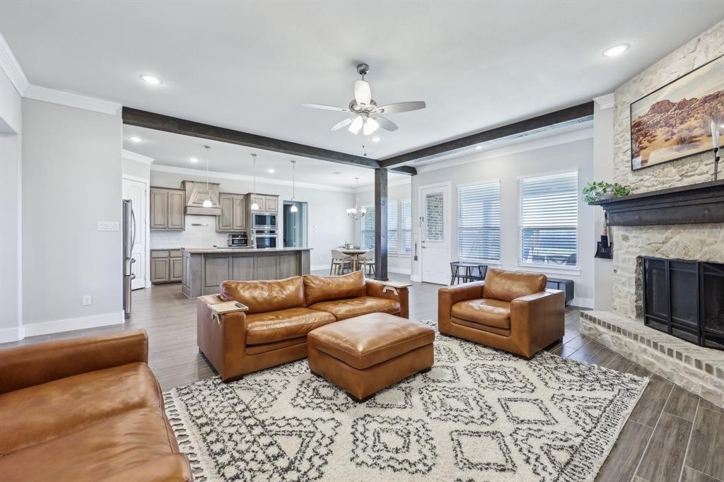 800 Majors Road Van Alstyne, TX 75495 - Photo 10 of 40 Living area with baseboards, wood finish floors, ceiling fan, a stone fireplace, and beamed ceiling