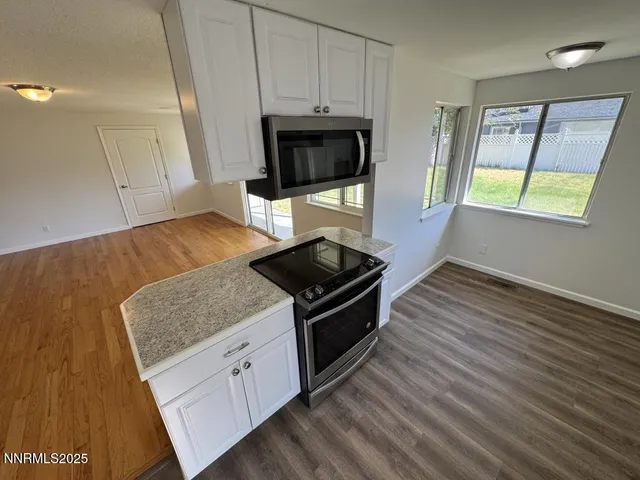 a kitchen with stainless steel appliances granite countertop a stove a microwave and a hard wood floors