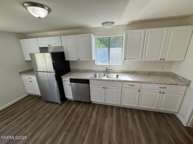 a kitchen with granite countertop a sink cabinets and stainless steel appliances