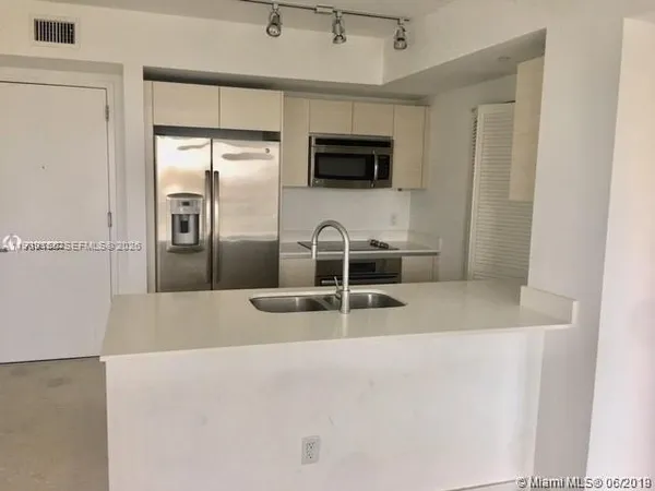 a view of a refrigerator in kitchen and a sink