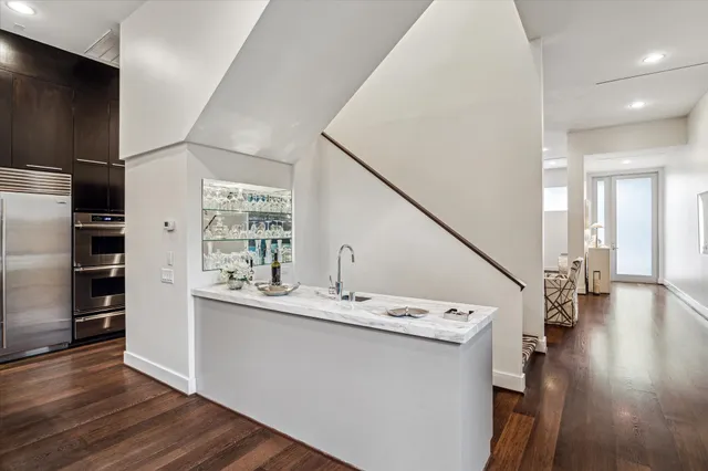a kitchen with a sink stainless steel appliances and wooden floor