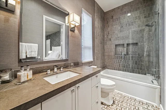 a bathroom with a granite countertop sink a toilet a mirror and shower