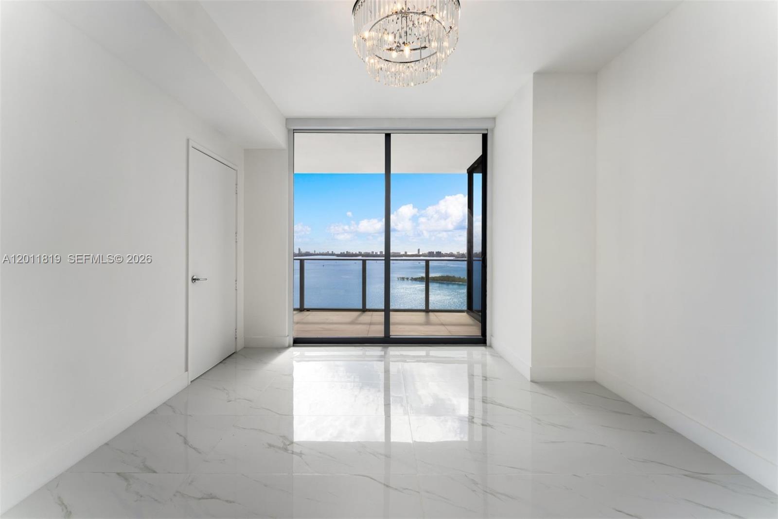 700 Northeast 24th Street, Unit 2504 Miami, FL 33137 - Photo 20 of 52 Serene primary suite offering unobstructed water views, direct terrace access, oversized walk-in closets, and floor-to-ceiling windows for a true 'mansion in the sky' feel.