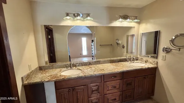 a bathroom with a granite countertop double vanity sink and a mirror
