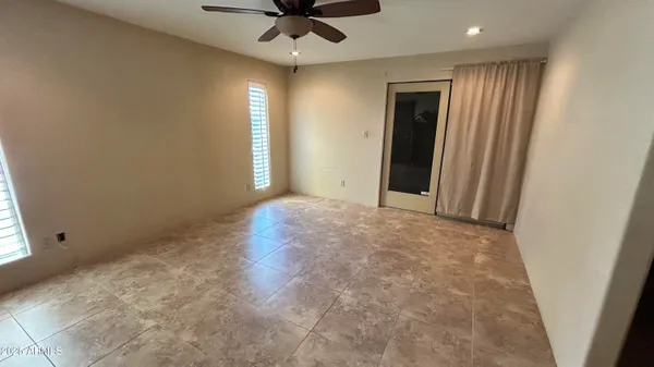 an empty room with a ceiling fan and windows