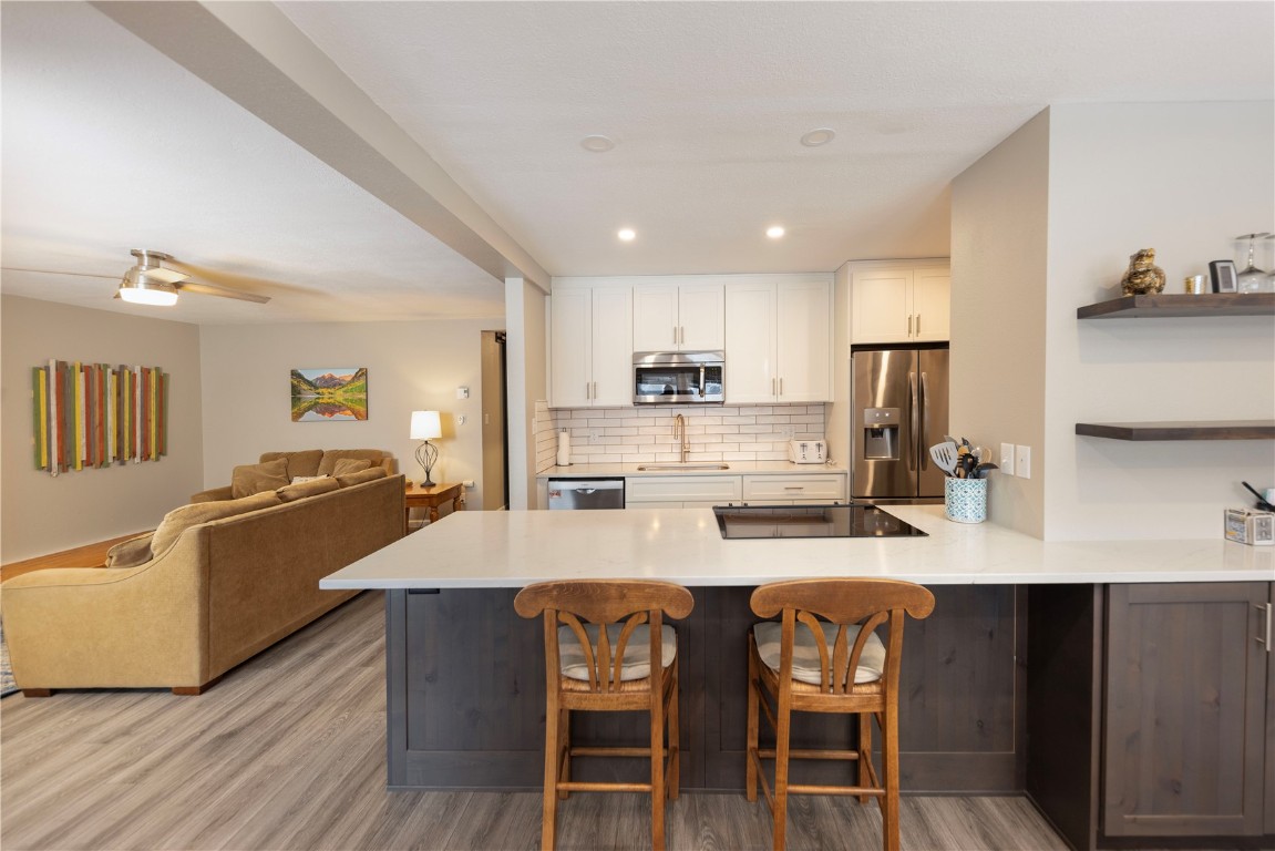 a large kitchen with granite countertop a dining table chairs wooden floor and stainless steel appliances