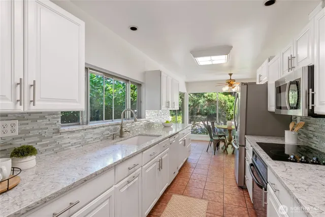 a very nice looking kitchen with granite countertop a large window and a sink