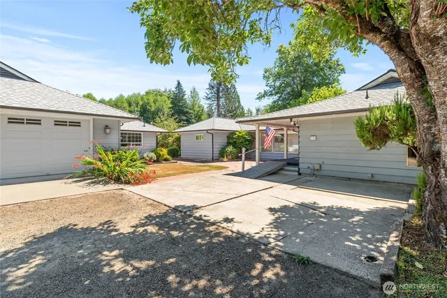 a backyard of a house with potted plants and large tree