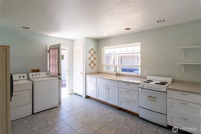a kitchen that has a lot of white cabinets and wooden floor