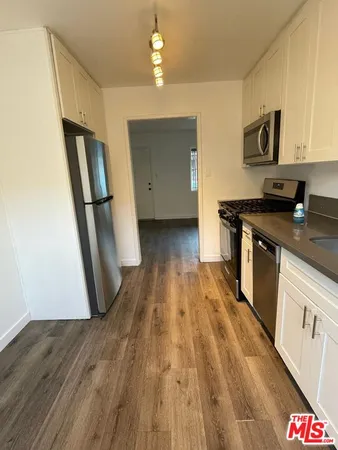 a kitchen with wooden floors and stainless steel appliances