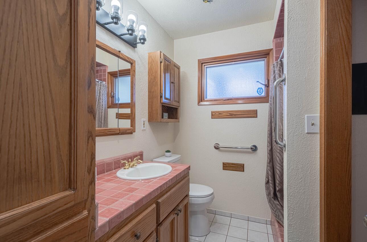 1527 Atherton Way Salinas, CA 93906 - Photo 40 of 64 a bathroom with a granite countertop sink a toilet a mirror and shower curtain