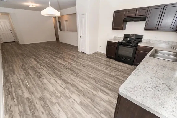 a kitchen with granite countertop a stove and a wooden floor