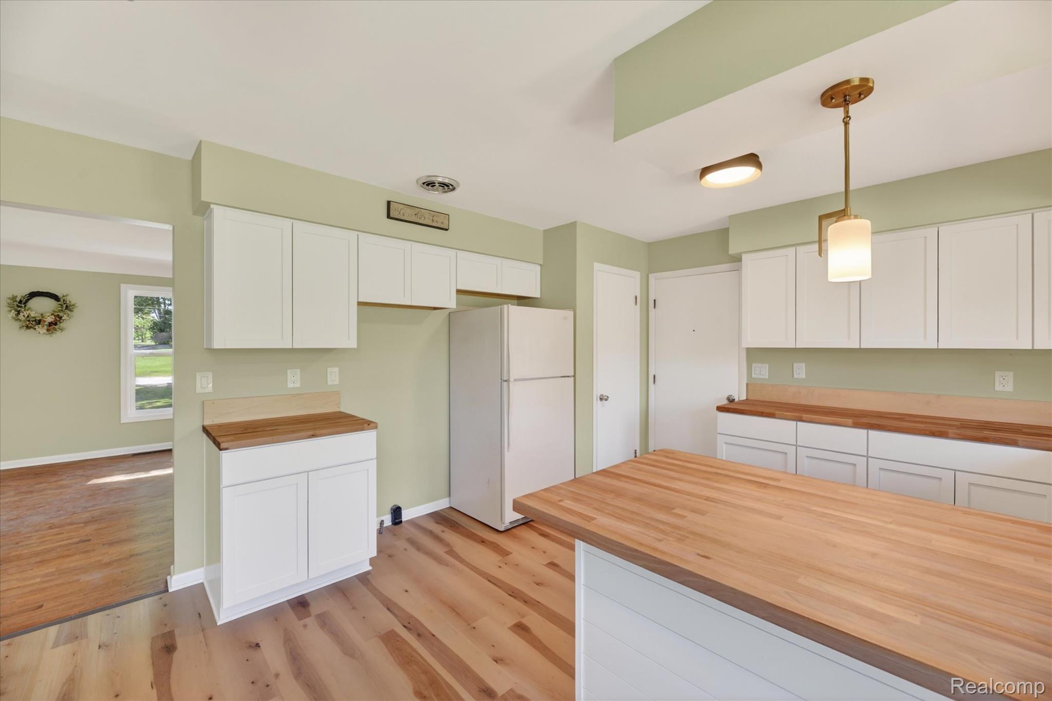 2250 Montague Road Davison, MI 48423 - Photo 17 of 45 Kitchen featuring wood-finish flooring, white cabinetry, butcher block countertops, white appliances, and a brass-tone pendant light fixture