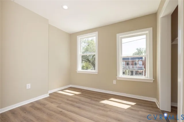 an empty room with wooden floor and windows