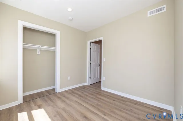 an empty room with wooden floor & closet