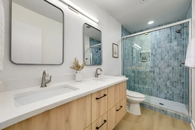 a bathroom with a double vanity sink toilet mirror and shower