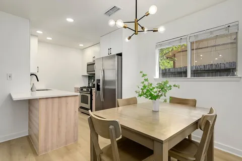 a kitchen with stainless steel appliances a dining table chairs and refrigerator