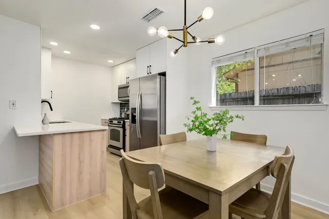 a kitchen with stainless steel appliances a dining table chairs and refrigerator