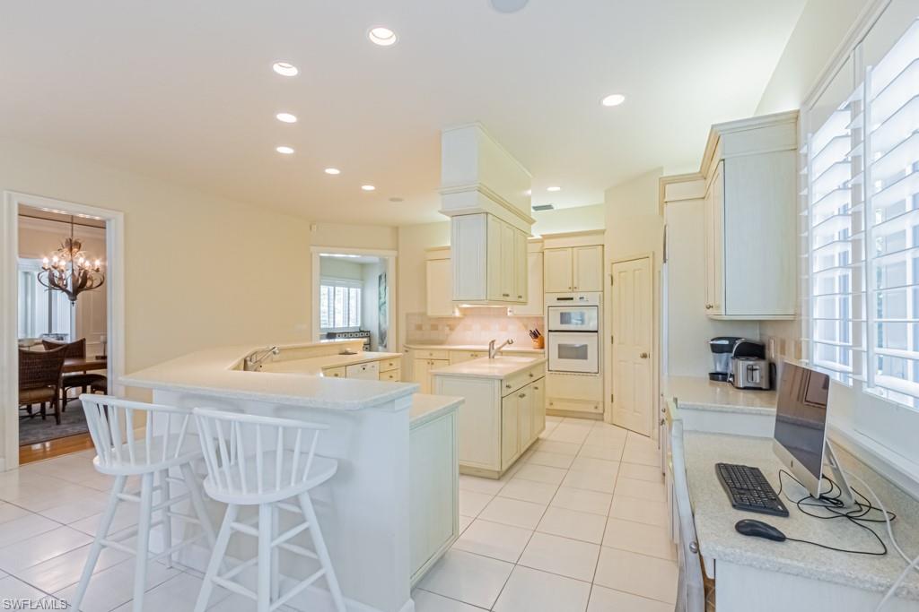 6974 Green Tree Drive Naples, FL 34108 - Photo 11 of 32 a kitchen with a dining table chairs and white cabinets