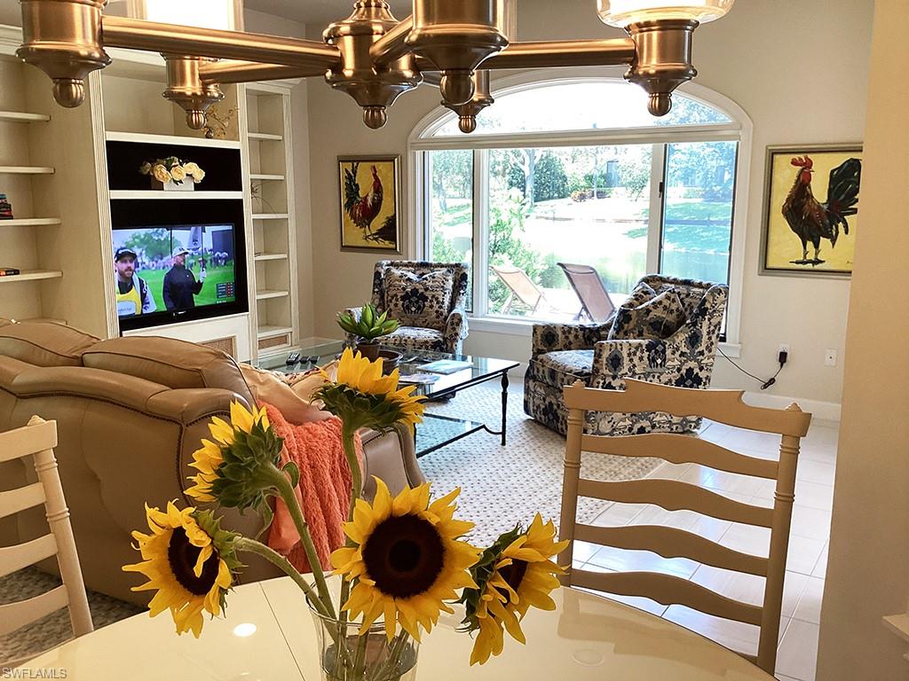 6974 Green Tree Drive Naples, FL 34108 - Photo 14 of 32 a living room with furniture a flat screen tv and a floor to ceiling window
