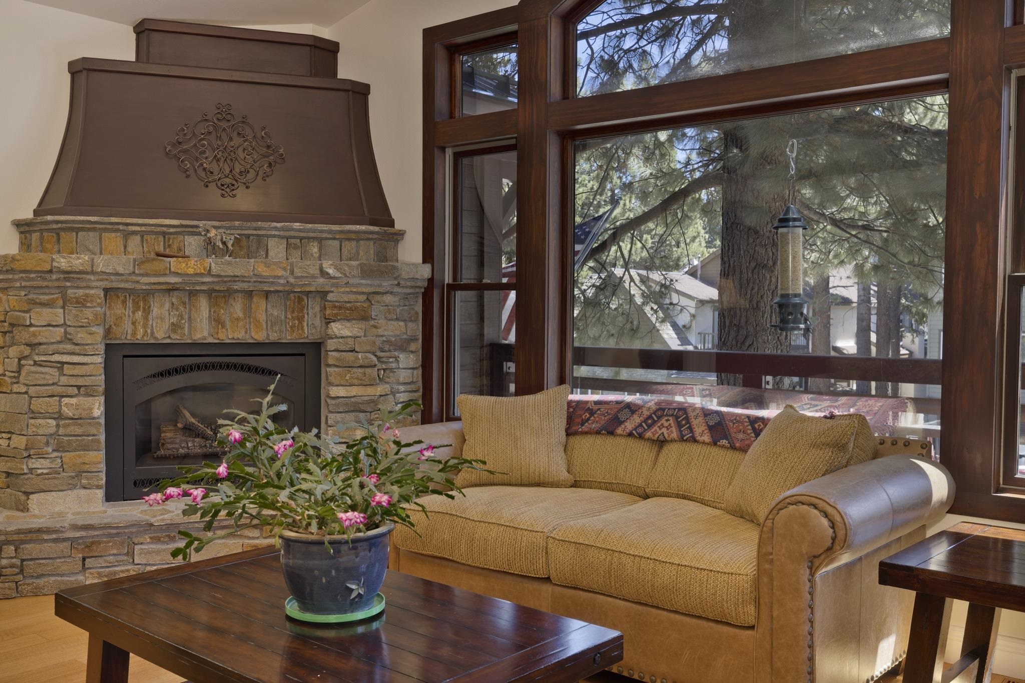 378 Ridge Way Mammoth Lakes, CA 93546 - Photo 8 of 43 Stone fireplace with an ornate metal hood, hardwood flooring, and large picture windows featuring wood trim
