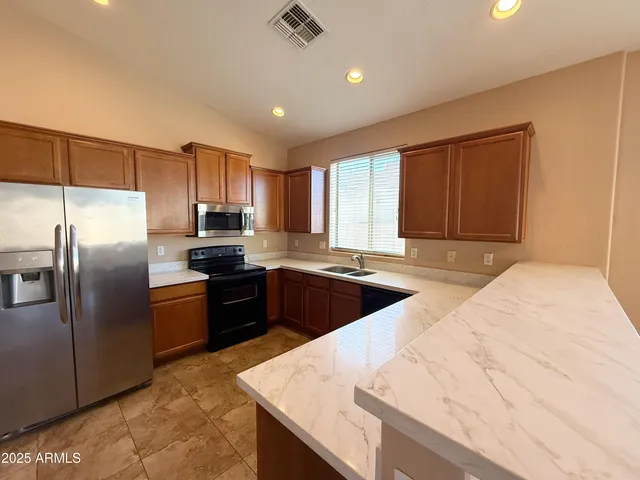 a kitchen with stainless steel appliances granite countertop a sink a stove a refrigerator cabinets and a sink