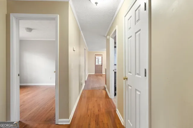 a view of a hallway with wooden floor and a bathroom