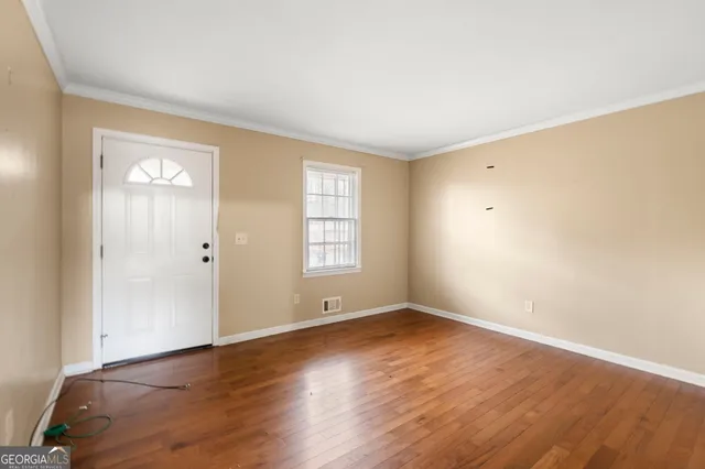 an empty room with wooden floor and windows