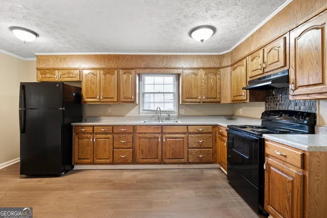 a kitchen with granite countertop a refrigerator stove top oven and sink