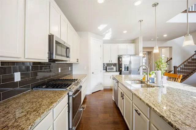 a kitchen with stainless steel appliances granite countertop a sink a stove and a wooden cabinets