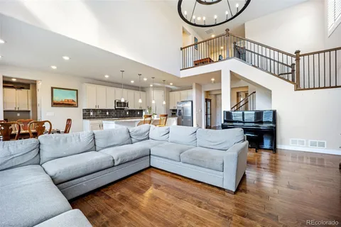 a living room with furniture kitchen view and a chandelier
