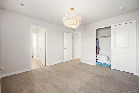 an empty room with a chandelier fan and wooden floor