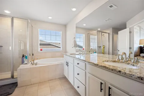 a bathroom with a granite countertop bathtub sink double and mirror