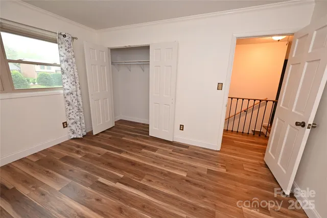 a view of empty room with wooden floor and fan