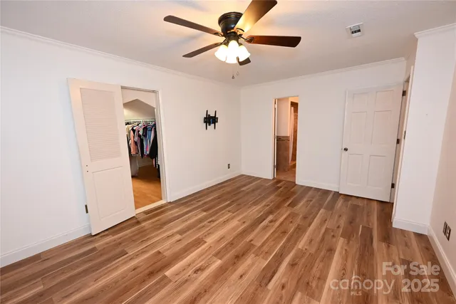 a view of a room with wooden floor and a ceiling fan