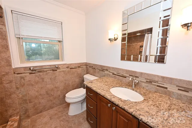 a bathroom with a granite countertop sink a toilet and a mirror