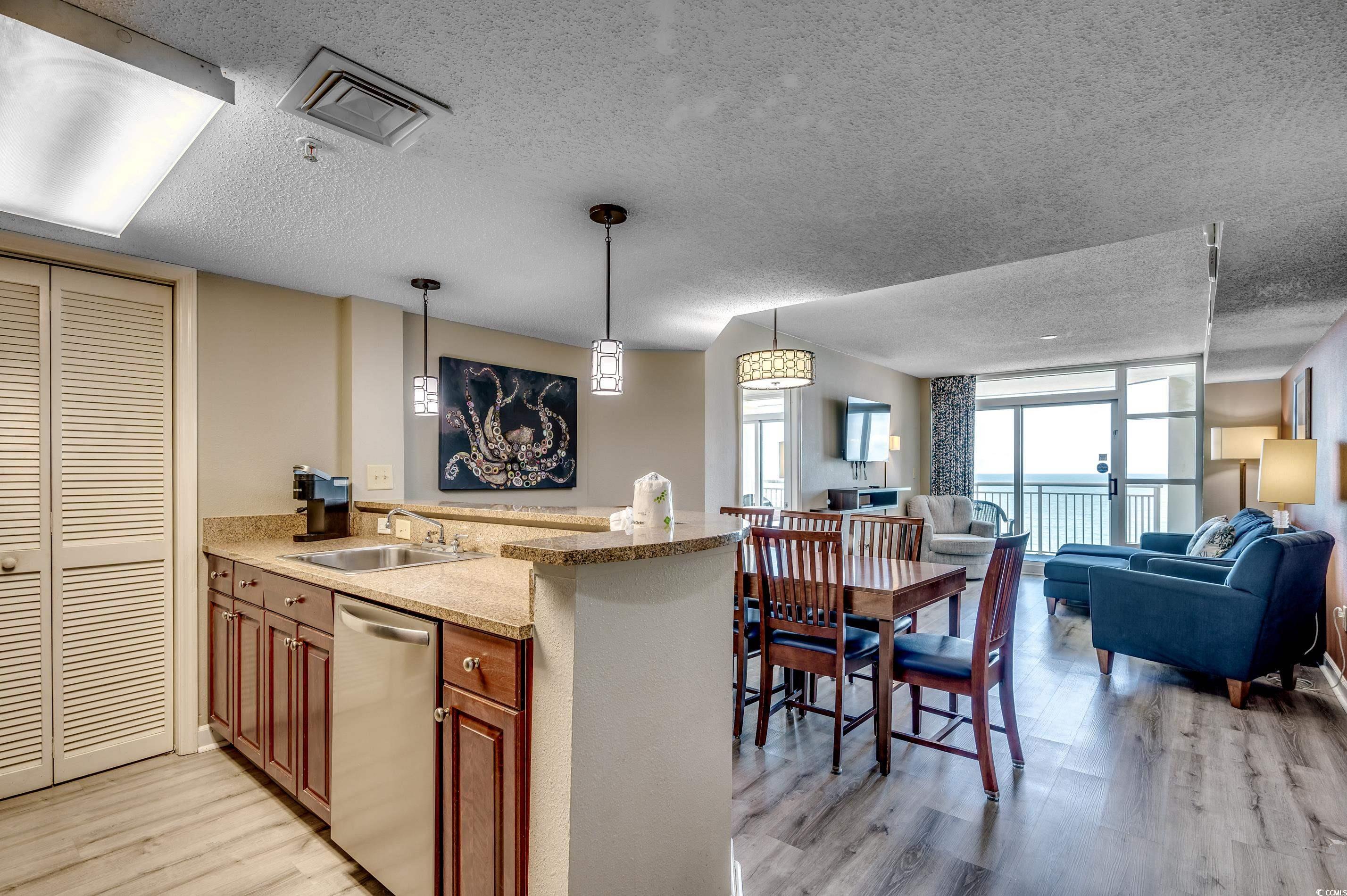 5200 North Ocean Boulevard, Unit 1037 Myrtle Beach, SC 29577 - Photo 4 of 40 Kitchen featuring a peninsula, light wood-style floors, decorative light fixtures, a textured ceiling, and stainless steel dishwasher