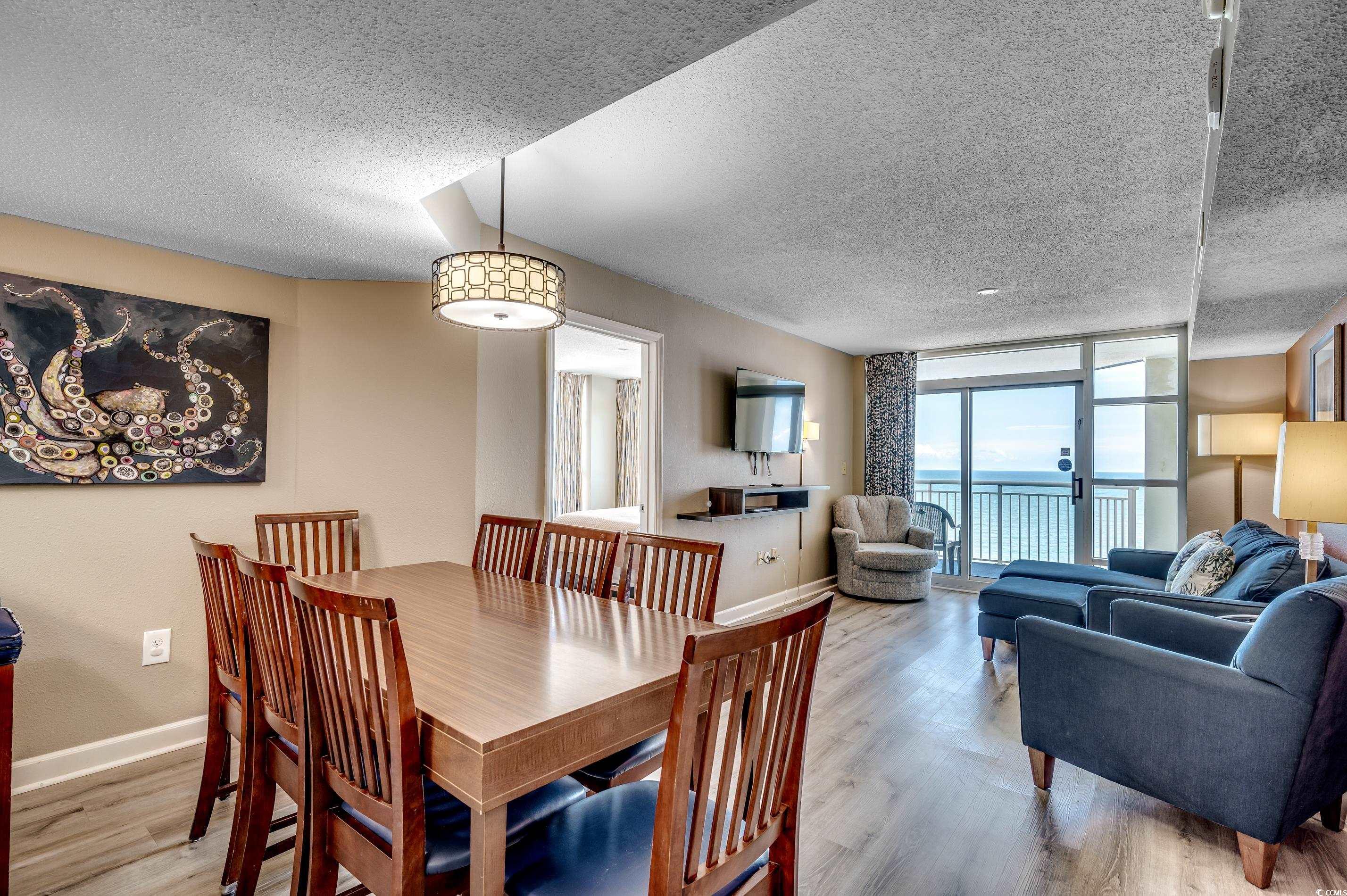 5200 North Ocean Boulevard, Unit 1037 Myrtle Beach, SC 29577 - Photo 5 of 40 Dining area featuring wood finished floors, a textured ceiling, and expansive windows