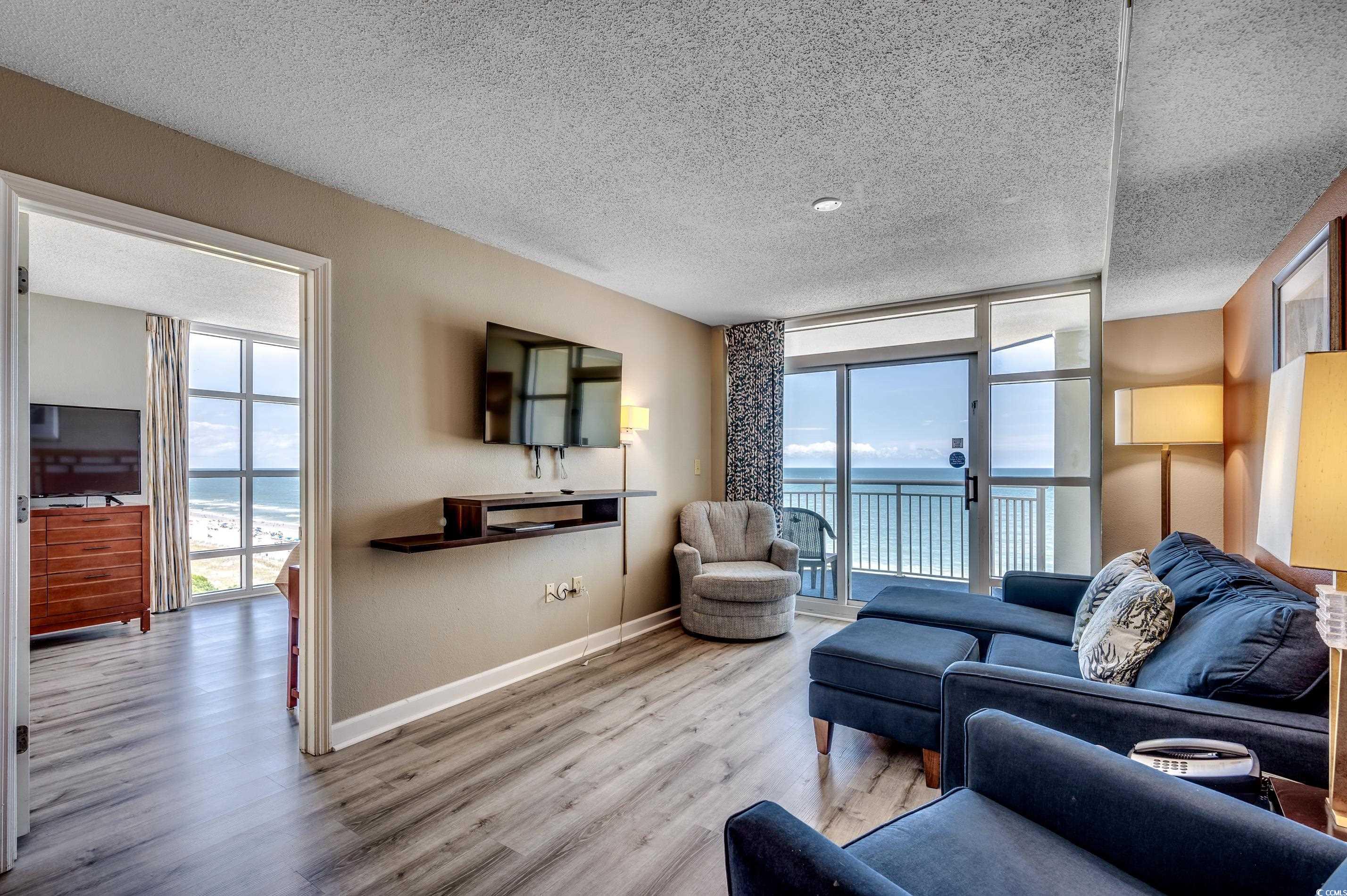 5200 North Ocean Boulevard, Unit 1037 Myrtle Beach, SC 29577 - Photo 7 of 40 Living area featuring a wall of windows, wood finished floors, and a textured ceiling