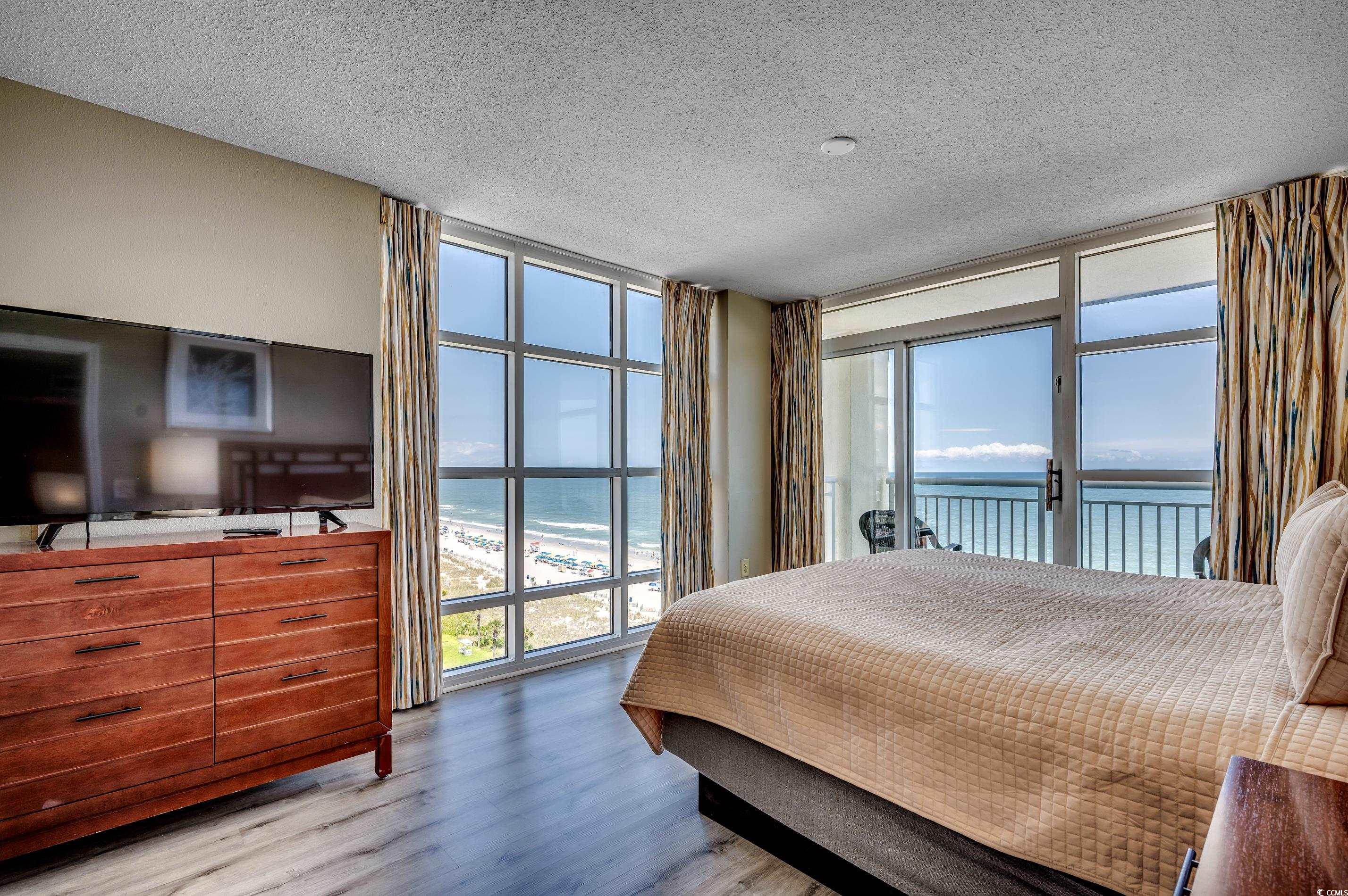 5200 North Ocean Boulevard, Unit 1037 Myrtle Beach, SC 29577 - Photo 8 of 40 Bedroom featuring expansive windows, a textured ceiling, light wood finished floors, and access to outside