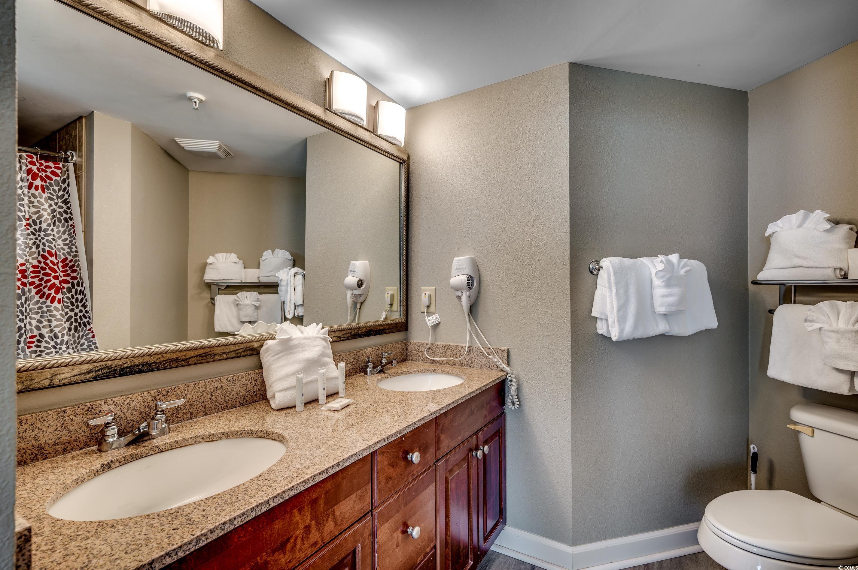 5200 North Ocean Boulevard, Unit 1037 Myrtle Beach, SC 29577 - Photo 10 of 40 Bathroom with double vanity, a textured wall, and curtained shower