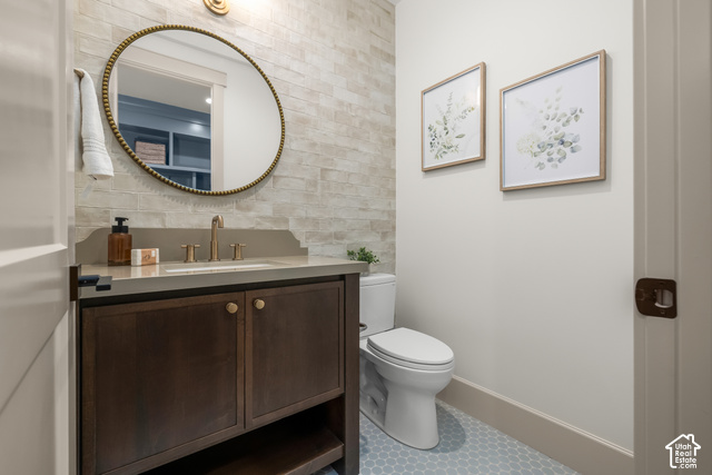 1175 North Elk Rdg Lane, Unit 201 Alpine, UT 84004 - Photo 26 of 38 Vanity with a light-toned countertop, a gold-toned faucet, a round wall-mounted mirror, and a tile accent wall