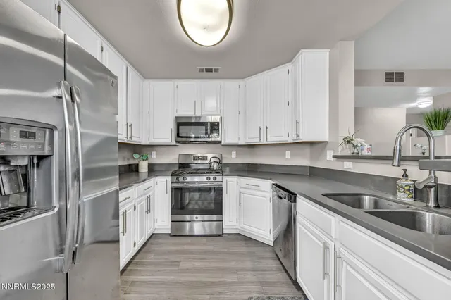 a kitchen with stainless steel appliances granite countertop a sink a stove a refrigerator and cabinets