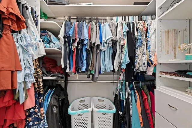 a view of walk in closet with clothes and shoes