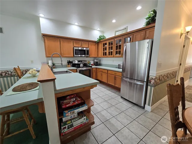 a kitchen with stainless steel appliances granite countertop a refrigerator a stove a sink and a dining table with garden view